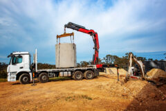 Articulating Boom ​ (Knuckle Boom) Cran Crane truck lowering a concrete septic sewage tank into the ground