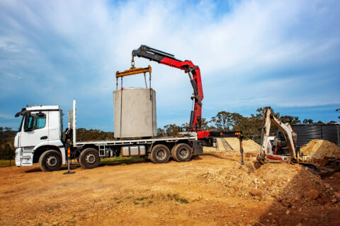 Articulating Boom ​ (Knuckle Boom) Cran Crane truck lowering a concrete septic sewage tank into the ground