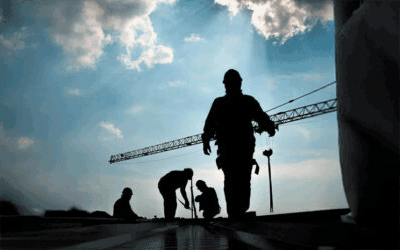 silhouette of construction workers on a job site with a blue sky with clouds in the background